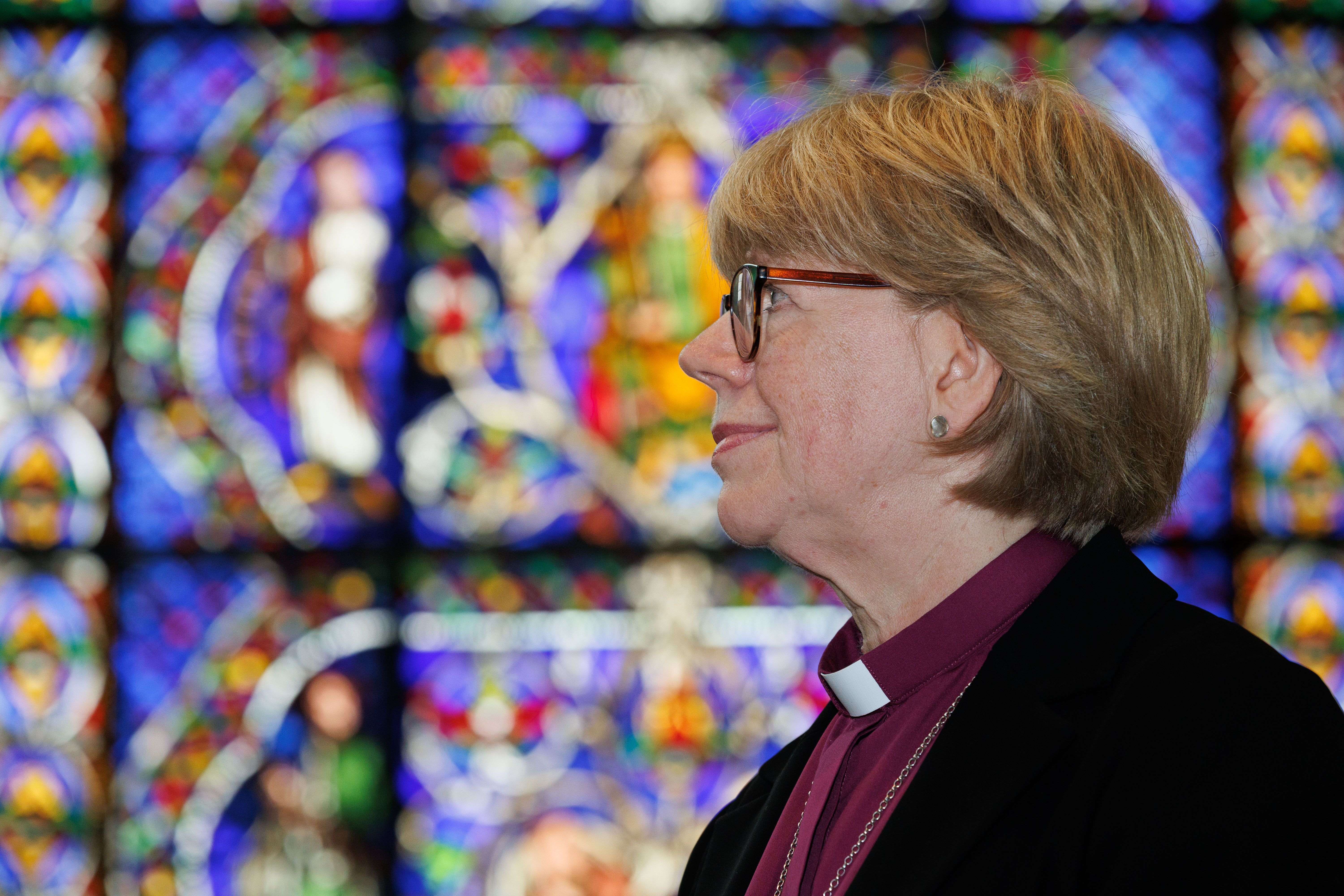 Profile of Dame Sarah Mullally in foreground stained glass of Canterbury Cathedral in background